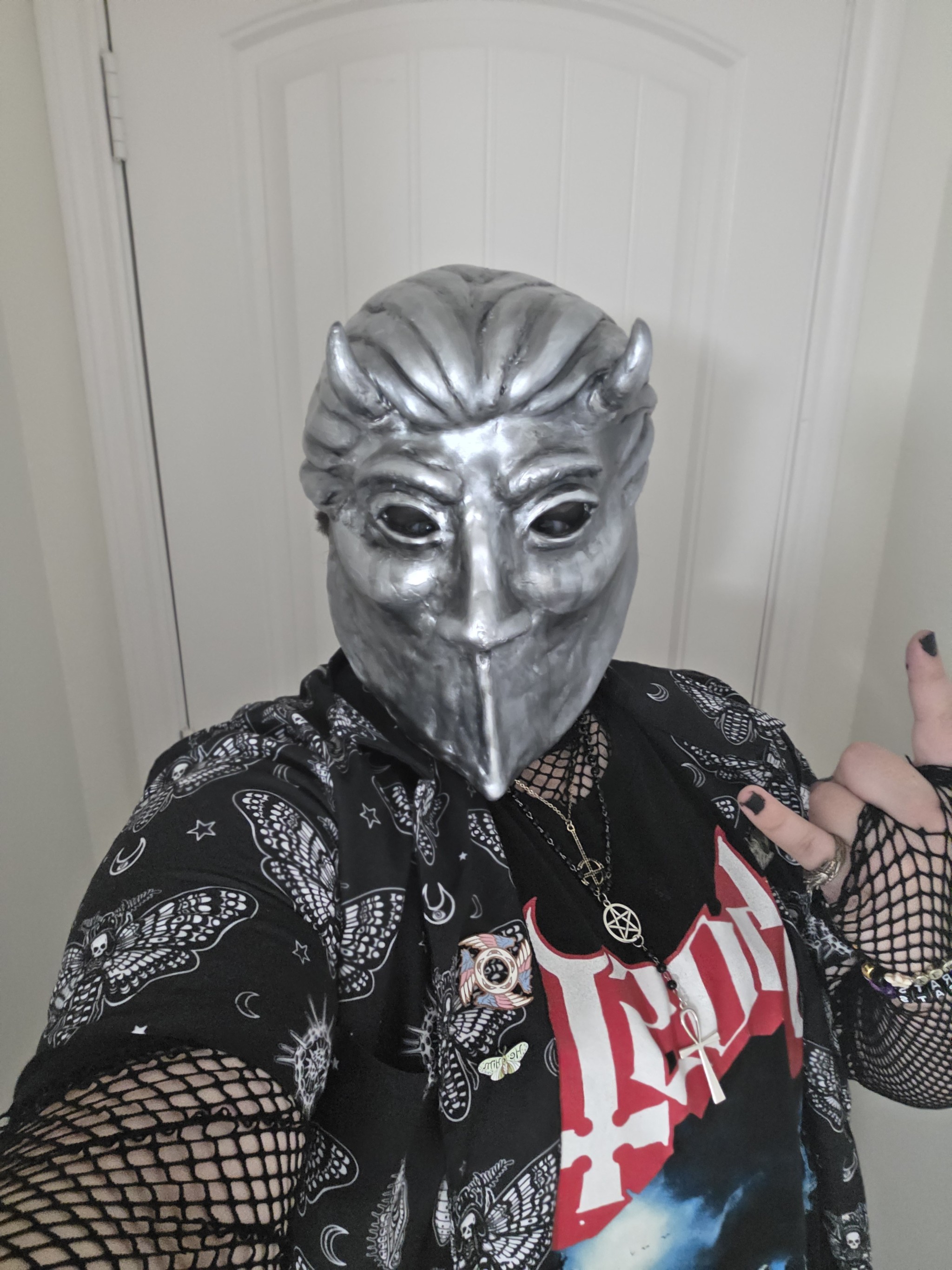 Tiercel Green in a Nameless Ghoul Mask holding up his hand in the Devil Horns sign